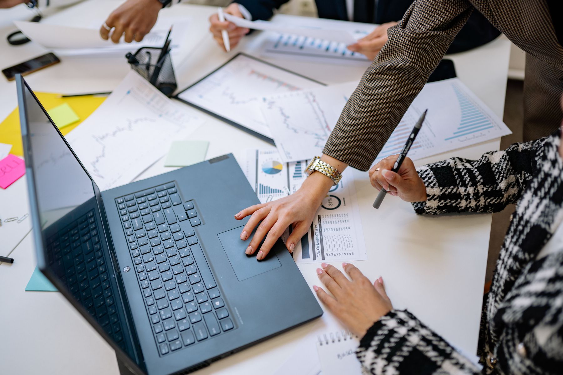 Laptop, reports and hands during a strategy session